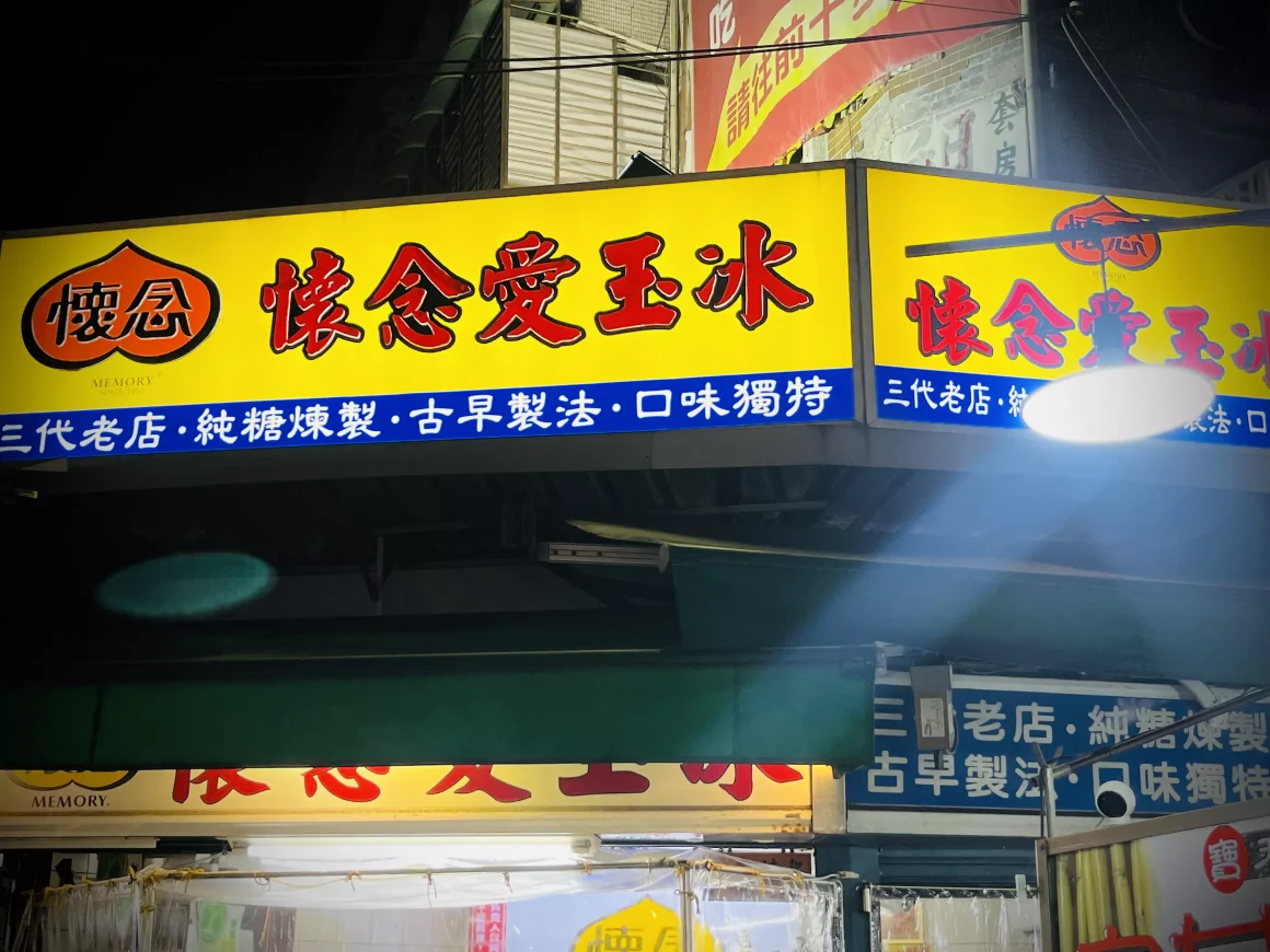 【萬華夜市】《懷念愛玉冰》:一半是回憶的召喚術,另一半是長大後的誠實豆沙包 11 萬華懷念愛玉冰的黃色招牌在夜晚中亮著,上面用紅色大字寫著店名,並標示著「三代老店、古早製法」等字樣。