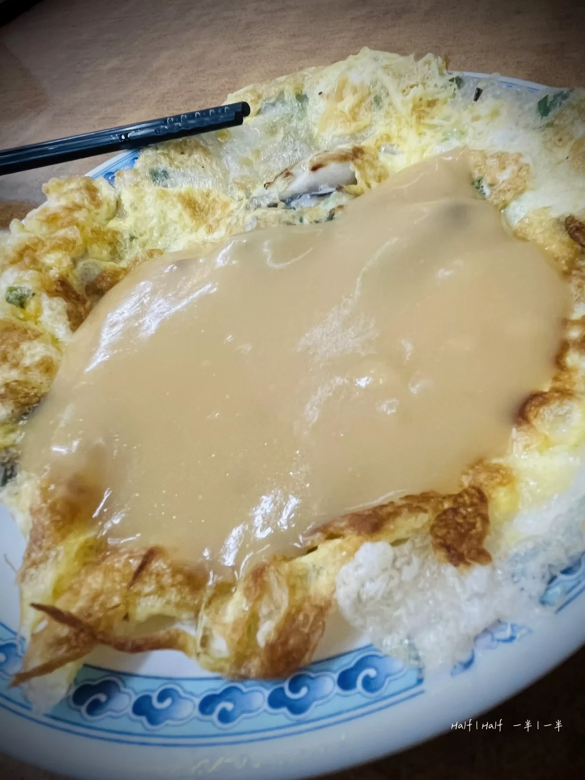 【板橋湳雅夜市】《蚵仔之家》評價:一半是神級鮮蚵,另一半是可惜的溫度? 23 一盤蚵仔之家的蚵仔煎,酥脆的蛋皮上淋滿了特製的粉色醬汁,盛裝在有著藍色花紋的盤子裡。