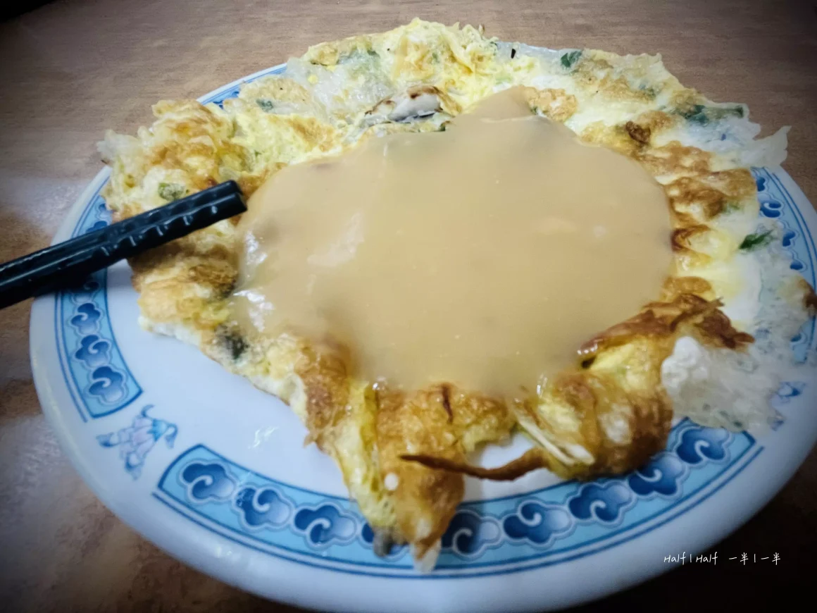 【板橋湳雅夜市】《蚵仔之家》評價:一半是神級鮮蚵,另一半是可惜的溫度? 18 一盤蚵仔之家的蚵仔煎,酥脆的蛋皮上淋滿了特製的粉色醬汁,盛裝在有著藍色花紋的盤子裡。